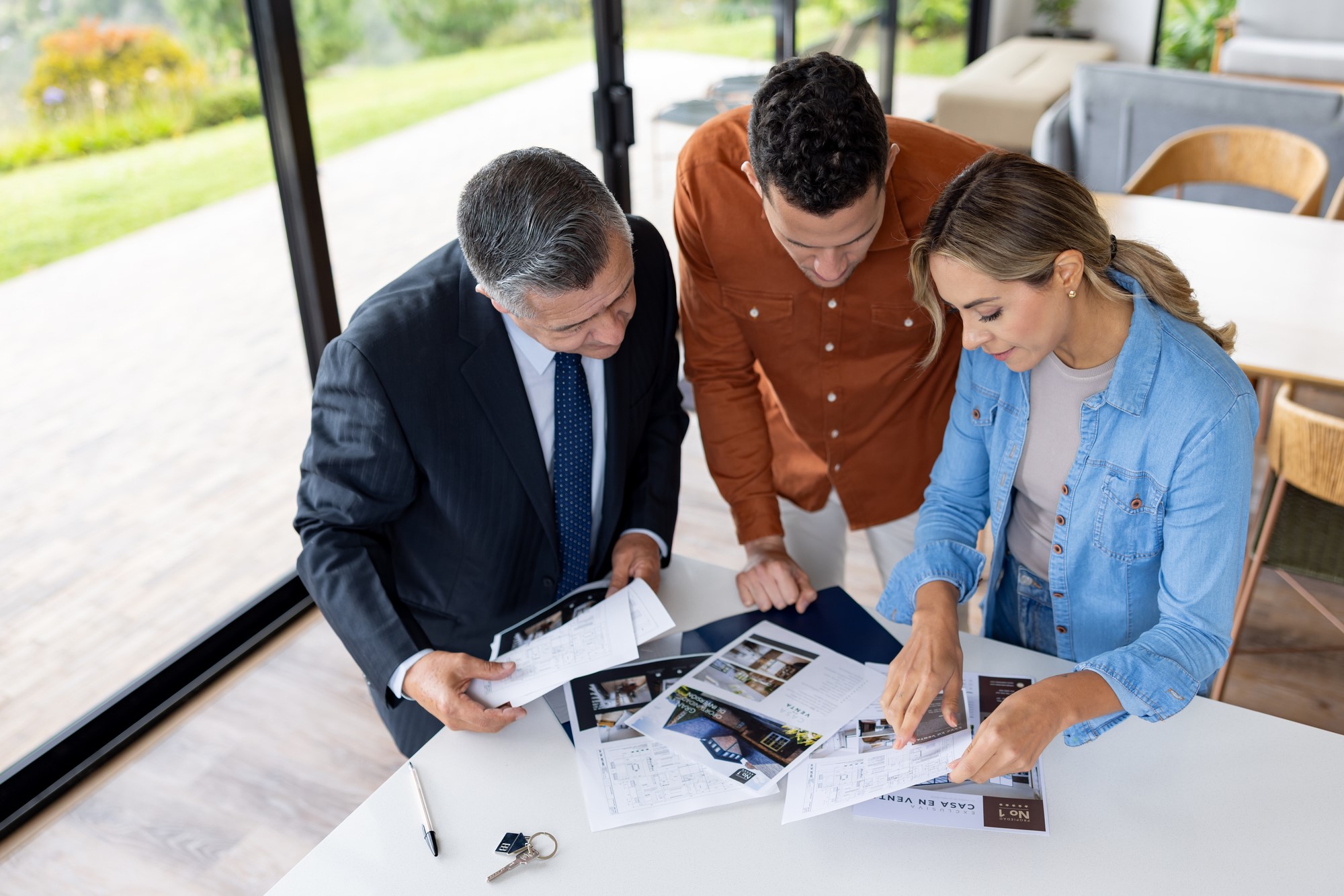 Couple looking at the blueprints of a house and asking questions to the real estate agent